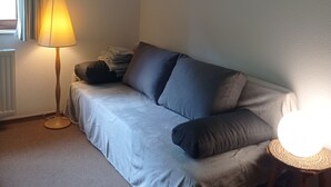 A small, cozy room with a single bed, a standing floor lamp, and a bedside table with a lamp. - Erholsame, Familienfreundliche 1-zi Fewo am Bach Bzw. am Ski-lift (Todtnau)