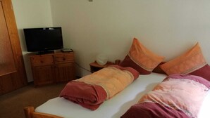 A bedroom with a wooden bed, a television on a wooden dresser, and a nightstand with a lamp. - Erholsame, Familienfreundliche 1-zi Fewo am Bach Bzw. am Ski-lift (Todtnau)