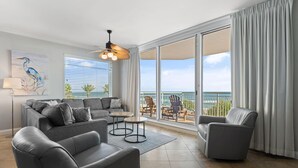 A modern living room with a gray sofa, two armchairs, and a coffee table. There is a large window with a view of the ocean. - Indigo West 301 (Pensacola)