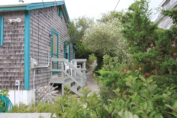 A wooden house with a blue trim and a small wooden staircase leading to a deck.