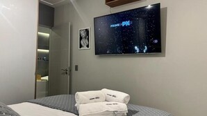 A hotel room with a bed, a wall-mounted TV displaying 'Prime Video', and a towel rack with towels. - PRIME LOK- SP FLAT VILA OLIMPIA (São Paulo)