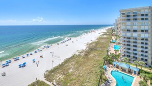 A beachfront hotel with a swimming pool, beach umbrellas, and a view of the ocean. - Bluewater 1101 (Orange Beach)