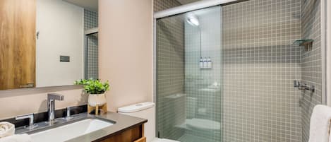 Un baño moderno con lavamanos doble, inodoro y ducha con mampara de vidrio.
