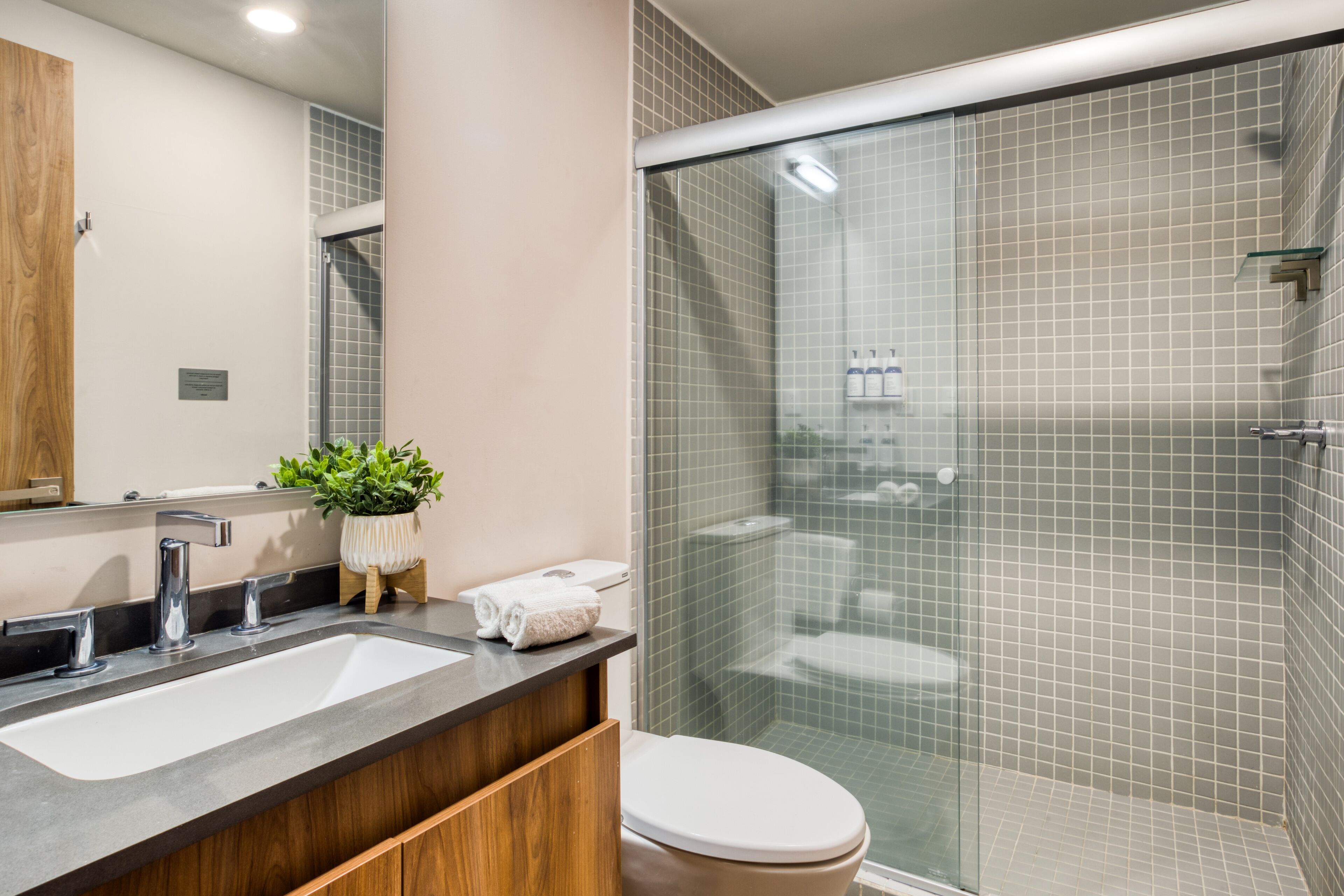 Une salle de bain moderne dotée d’un meuble-lavabo à deux vasques, de toilettes et d’une douche à l’italienne.