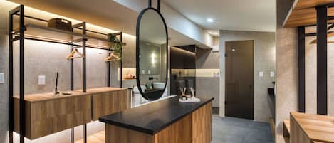 A modern bathroom with a wooden vanity, a large mirror, and a built-in shower area.