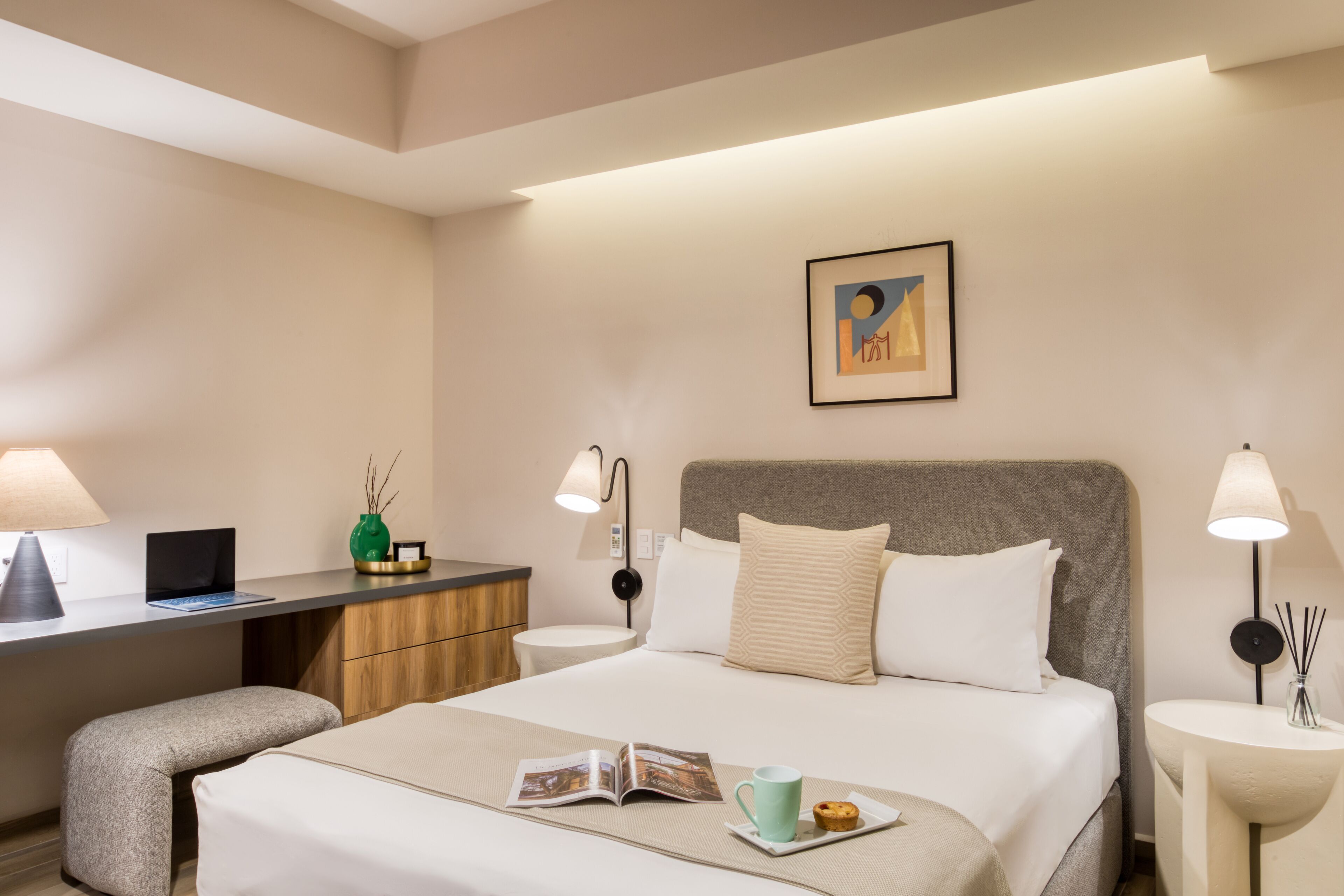 A hotel room with a bed, bedside tables, a desk, and a chair.