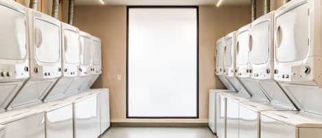 A row of white laundry machines with a large window in the center.