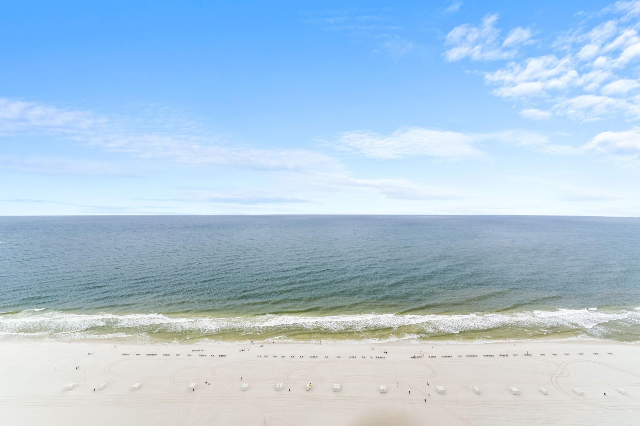 Ein Strand mit blauem Himmel und ruhiger See.