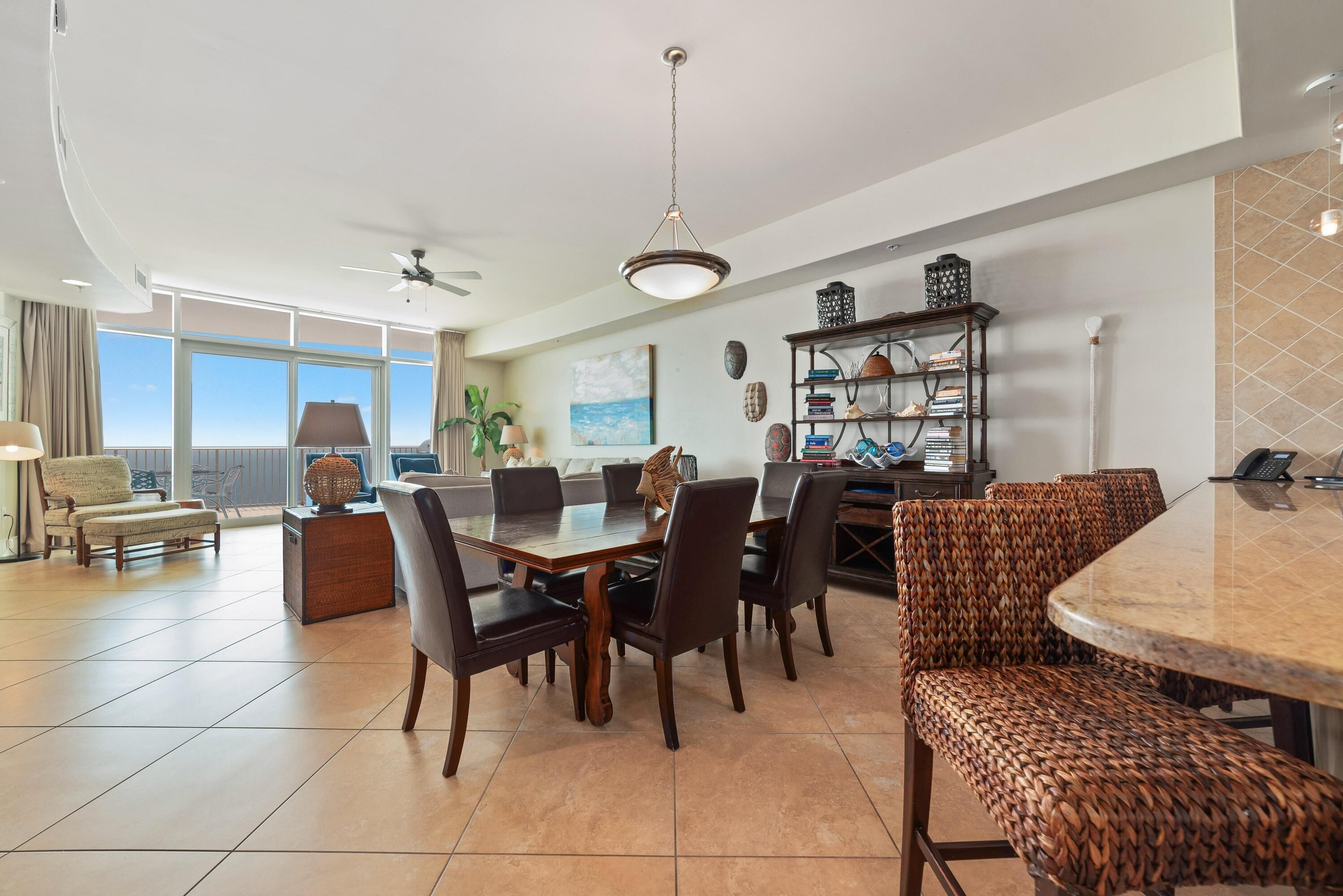 A spacious living area with a dining table, comfortable seating, a ceiling fan, and a view of the outdoors.
