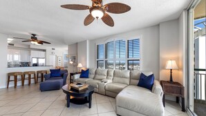 A spacious living room with a large sectional sofa, a coffee table, and a ceiling fan. - Beach Colony East 10A (Pensacola)