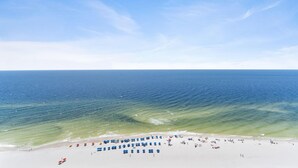 A beach with rows of blue and red beach umbrellas and a sandy shoreline.