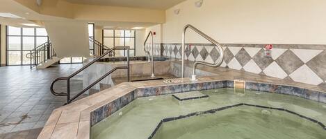 A swimming pool with a tiled edge, a metal handrail, and a stairway leading to an upper level.
