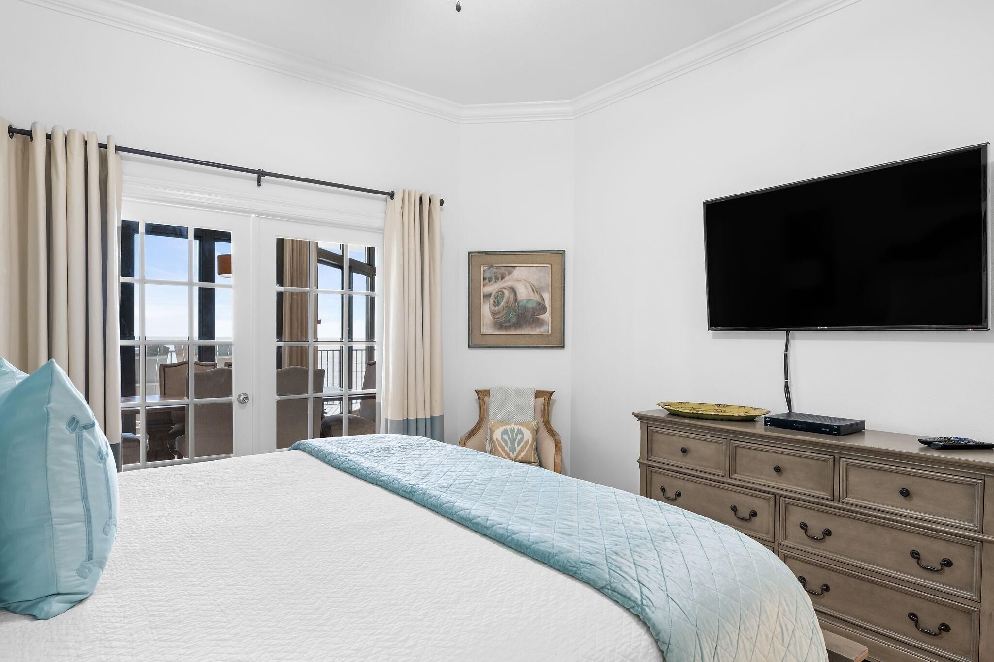 Une chambre d’hôtel avec un grand lit, un téléviseur à écran plat, une commode et une vue sur l’extérieur, accessible par une porte coulissante.