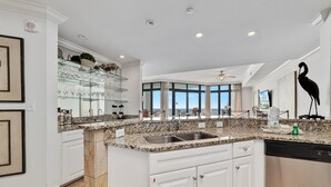 A modern kitchen with white cabinetry, granite countertops, and a large island with a sink.