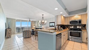 A spacious kitchen with a large island, stainless steel appliances, and a view to the outside. - Perdido Sun 904 (Pensacola)