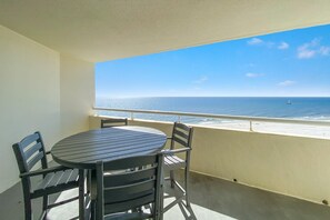 A balcony with a table and chairs, overlooking a beach with a clear view of the ocean and a distant boat. - Perdido Sun 904 (Pensacola)