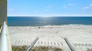 A beach with a clear sky, a sandy shore, and a metal walkway leading to the water. - Perdido Sun 904 (Pensacola)