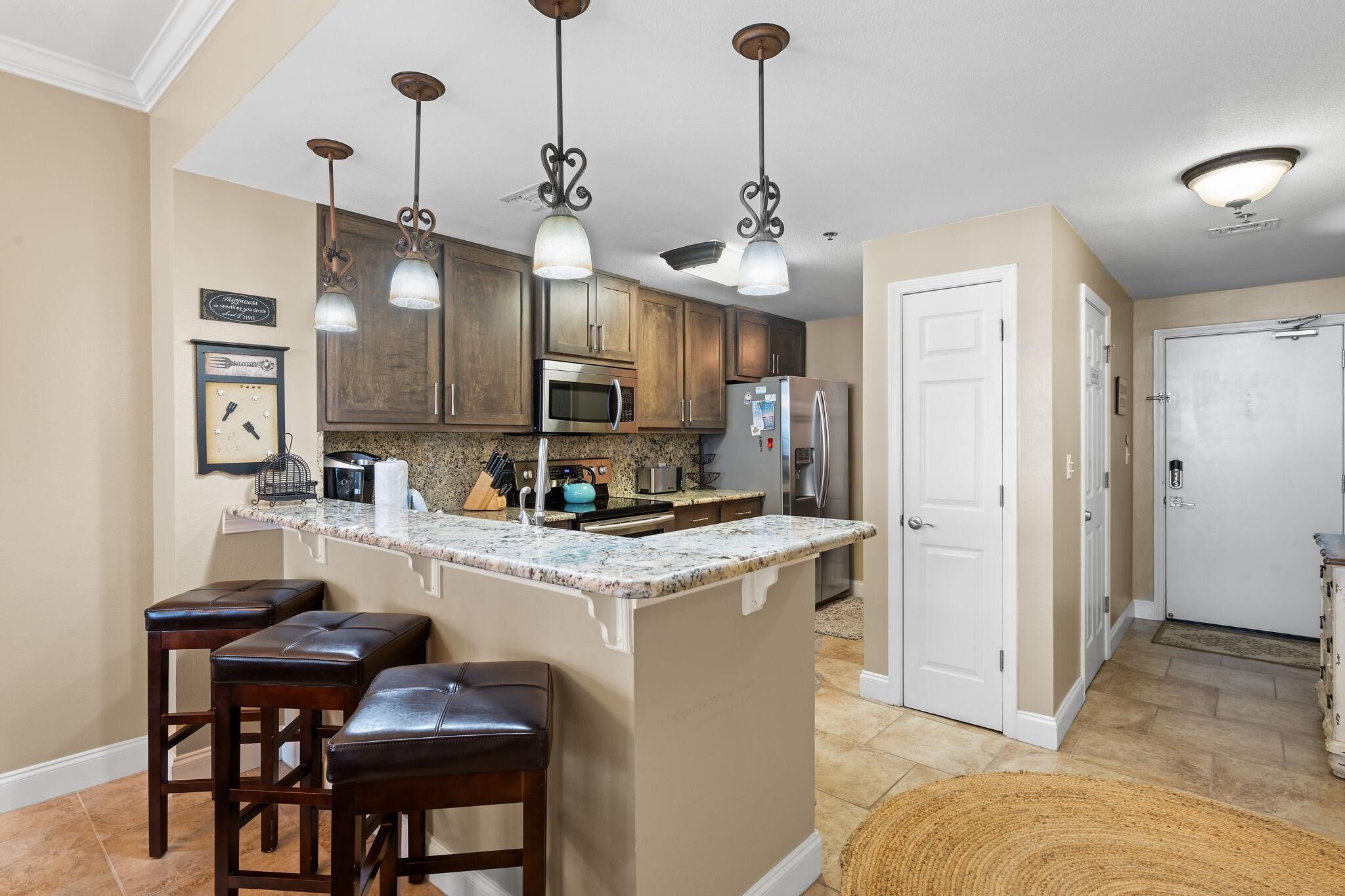 A kitchen with wooden cabinets, a granite countertop, and a central island with stools.