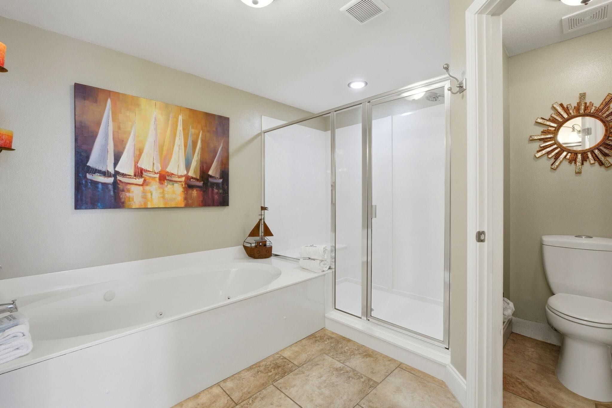 A bathroom with a bathtub, a glass-enclosed shower, a toilet, and a wall-mounted mirror.