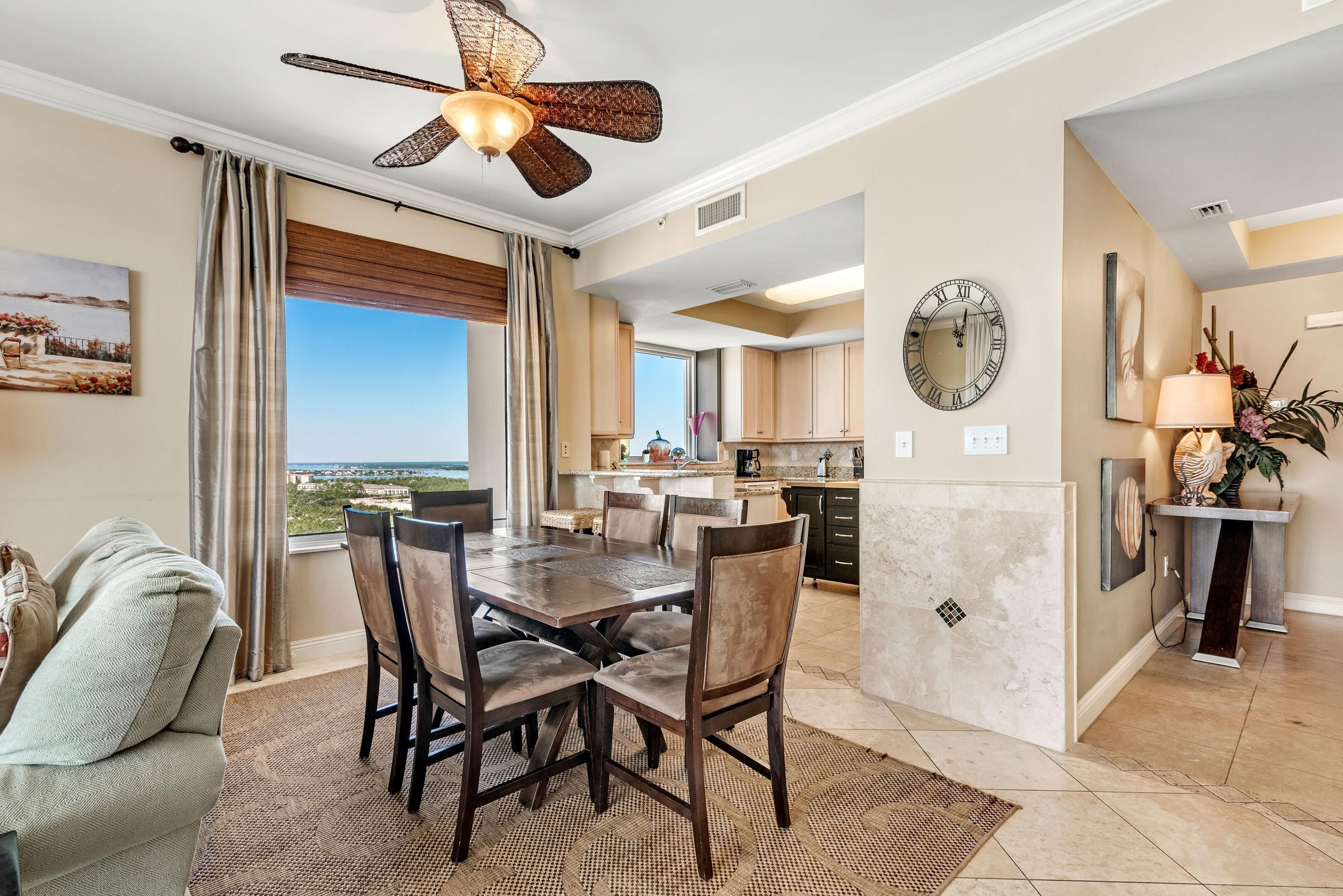 A spacious dining area with a large table and chairs, a ceiling fan, and a view of the outdoors.