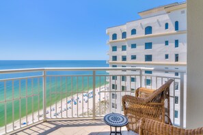 Ein Balkon mit Blick auf Strand und Meer, Korbmöbel und ein Fliesenboden.