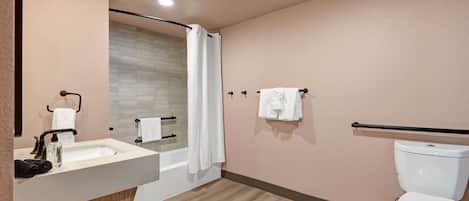 A modern bathroom with a sink, mirror, shower, and toilet.