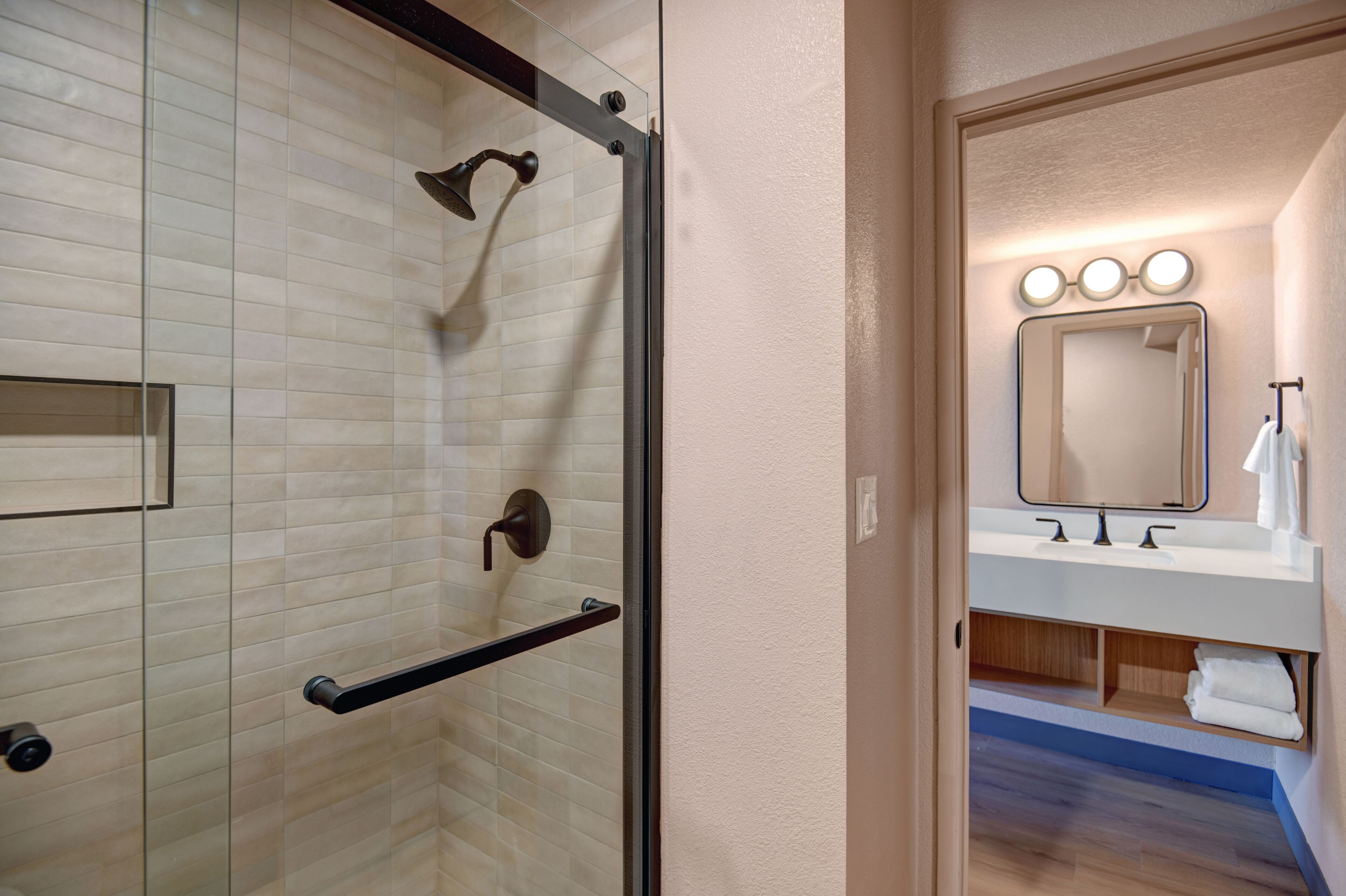 Un bagno moderno con cabina doccia in vetro, un mobile lavabo con specchio e un lavandino.