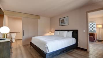 A bedroom with a wooden bed, a bedside table, a lamp, and a framed picture on the wall.