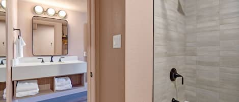 A bathroom with a vanity, mirror, and shower.