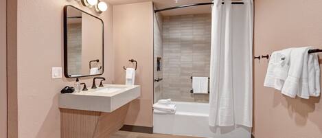 A modern bathroom with a vanity, mirror, shower, and towel rack.
