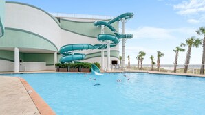 Una piscina con un tobogán de varios niveles y palmeras al fondo.