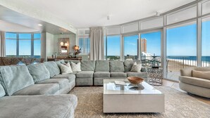 Un salón amplio con un sofá modular grande, una mesa de centro y vista a la playa.