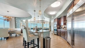 Una cocina moderna con una isla central, electrodomésticos de acero inoxidable y una zona de bar con asientos.