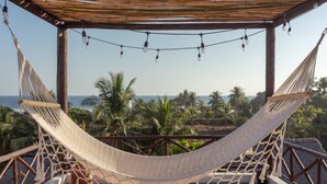 A hammock under a wooden pergola with string lights, overlooking a beach with palm trees and the ocean. - Mangomiel (Sipacate)