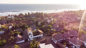 A coastal village with thatched-roof houses, a central building with a dome, and a view of the sea. - Mangomiel (Sipacate)