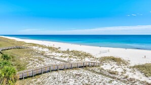 A beach with a wooden boardwalk leading to the shore, clear blue water, and a sandy beach. - Shipwatch A504 (Pensacola)