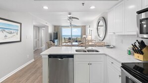 A modern kitchen with white cabinetry, a dishwasher, and a stove. There is a view of the ocean through large windows. - Perdido Sun 200 (Pensacola)