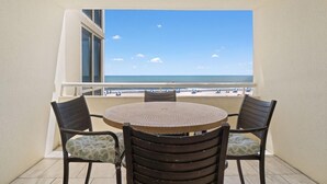 A balcony with a round table and four chairs, overlooking a beach with people and umbrellas. - Perdido Sun 200 (Pensacola)
