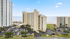 A high-rise hotel with multiple floors, a parking lot, and a view of the ocean. - Perdido Sun 200 (Pensacola)