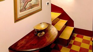 Una escalera con piso a cuadros rojo y amarillo, una obra de arte enmarcada en la pared y una lámpara de pared.