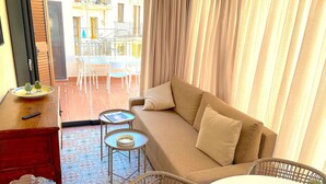 Una sala acogedora con un sofá, una mesita y un sillón de mimbre.