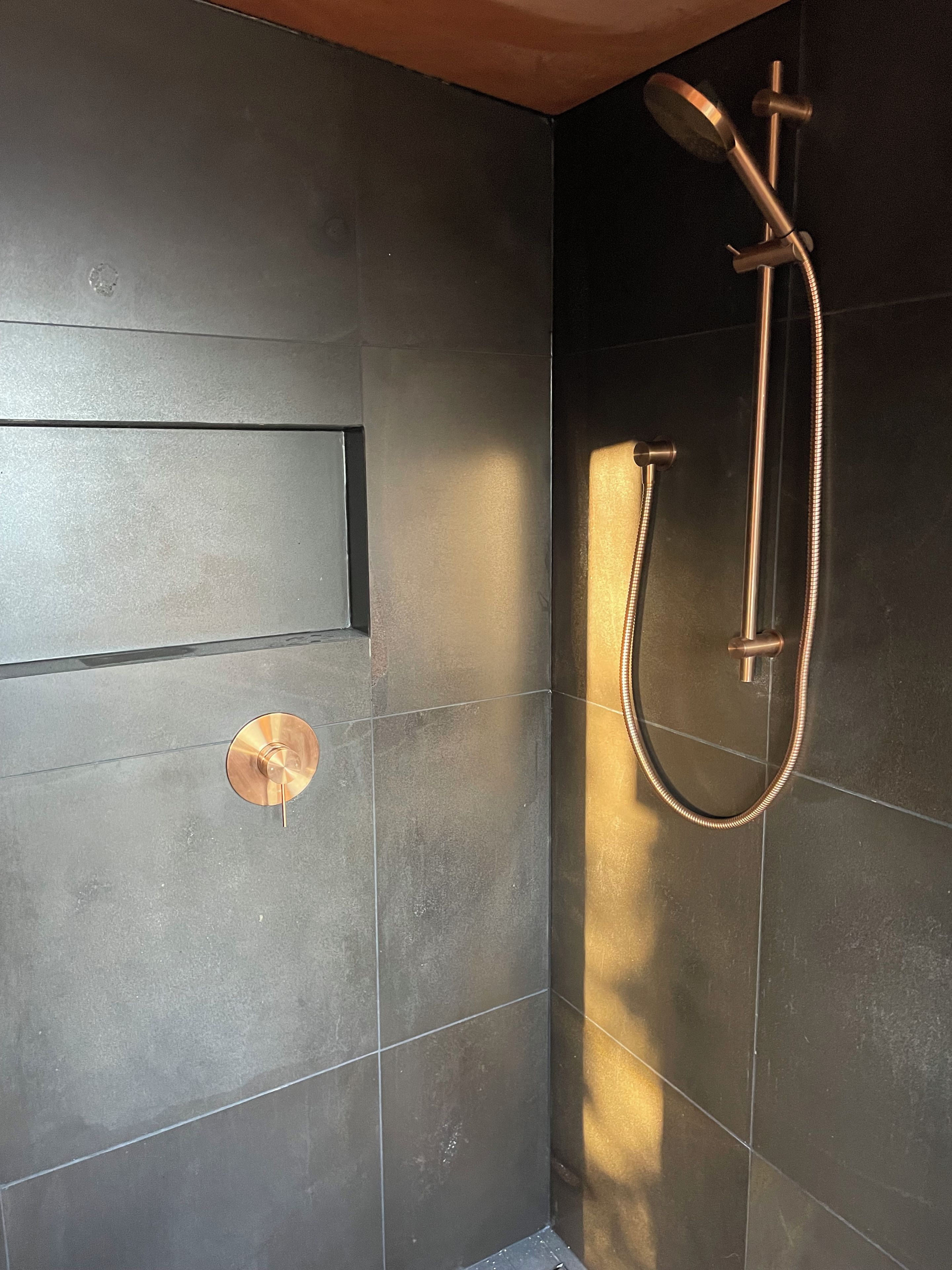 A modern shower with a handheld showerhead and a flexible hose.