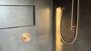 A modern shower with a handheld showerhead and a flexible hose.