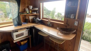 A wooden cabin kitchen with a built-in microwave, a sink, and a window overlooking greenery.
