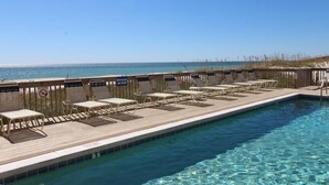 Ein Poolbereich mit Liegestühlen und einer Holzterrasse mit Blick auf den Ozean.