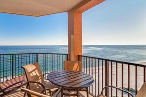 Enjoy the ocean view from this balcony with a table and chairs.