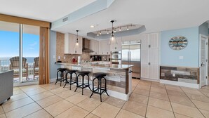A modern kitchen with a large island, bar stools, and a view of the city. - Caribe D1110 (Orange Beach)