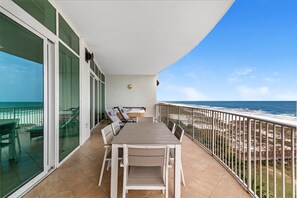 Un balcón con mesa y sillas, con vista a la playa y al océano.