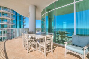 Ein Balkon mit Tisch und Stühlen, einer Couch und Blick auf das Meer.