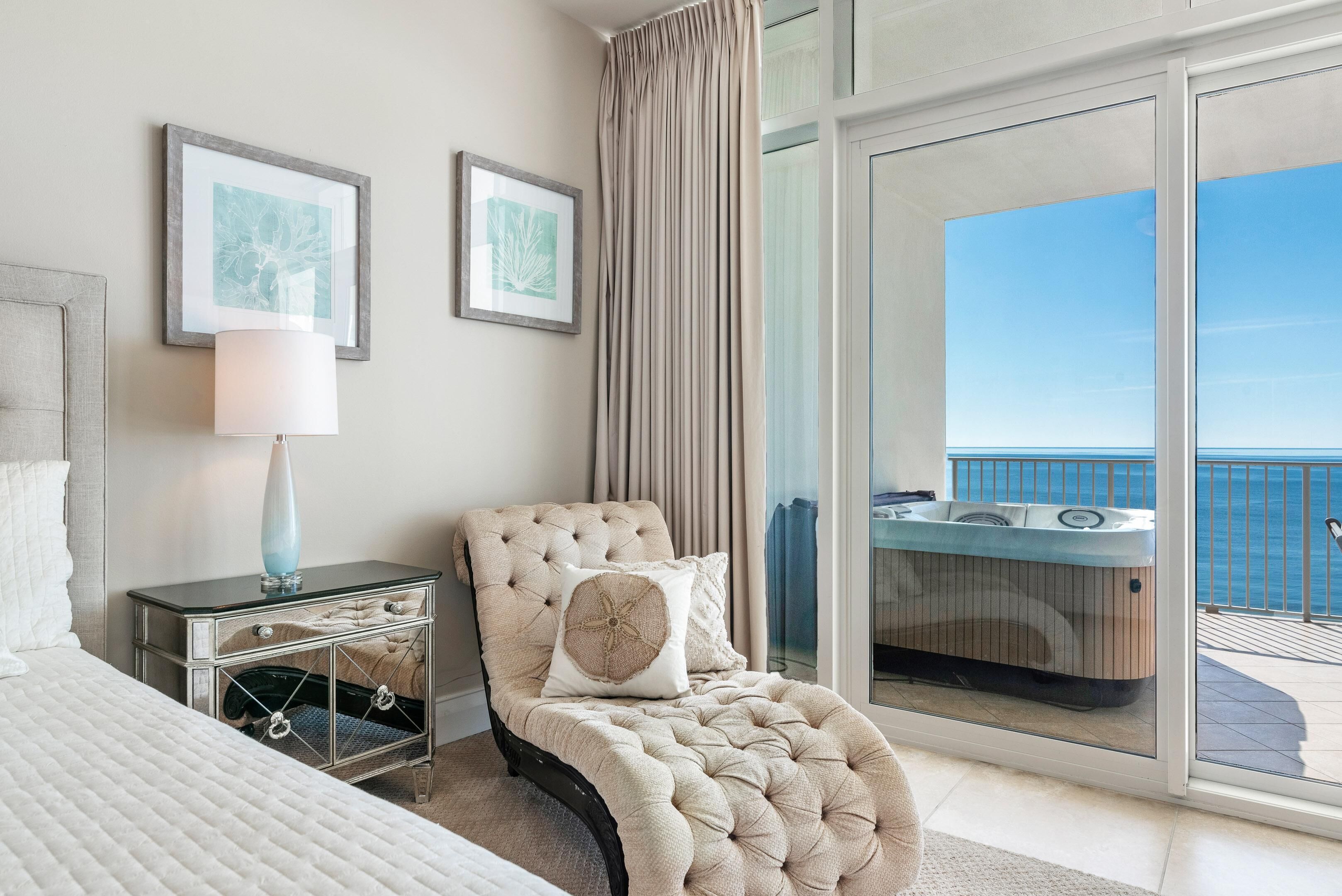 Une chambre avec un lit, une table de chevet, une chaise et une vue sur un balcon doté d’un jacuzzi.